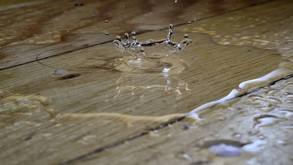 Water droplet landing on wood floor planks