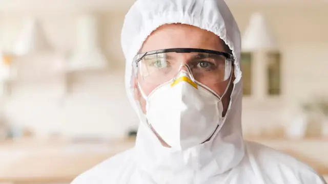 Worker in a hooded suit, safety glasses and an N95 respirator